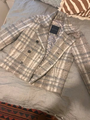 Rutig skepparkavaj Tommy Hilfiger - Snygg skepparkavaj i grått och beige rutmönster från Tommy hilfiger. Köpte den på Plick för 1000kr men har aldrig kommit till användning. Väldigt fint skick. Storlek M men skulle säga M/L beroende på hur man vill att den ska sitta och om man har någon tjock tröja under. Den är i ull och perfekt för hösten/vintern och håller dig varm.