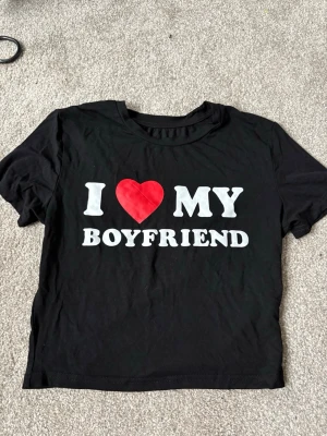 Svart t-shirt med I ❤️ MY BOYFRIEND-tryck - Denna T-shirt älskar jag med, trycket för tröjan unik, tröjan får också en lite magtröja känsla. Använd ett par gånger men inget som märks. Storlek M. Kan få 50% rabatt om man köper både linnet och T-shirten i samma tryck🔥🔥