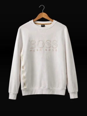 Vit sweatshirt från Hugo Boss - Stilren vit sweatshirt från Hugo Boss med broderad logga på bröstet och diskreta detaljer längs sidan. Tröjan har rund halsringning, långa ärmar och ribbade muddar. Perfekt för en clean och avslappnad look.
