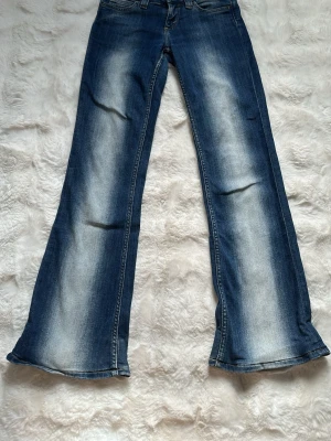 Blå utsvängda jeans  - Säljer dessa snygga jeansen från Weekday (Cheap monday . Jeansen har klassisk femficksmodell och en cool tvätt med ljusare partier längs benen. Jeansen är i storlek W25/32 men är uppsydda. Innerbenslängden är ca 73 cm. Använda men i fint skick!
