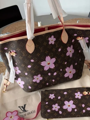 Väska  - Helt ny Neverfull väska med murakami blommor. Väskan är i äkta läder och har röd insida