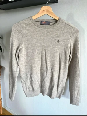 Beige Morris tröja - Beige Morris tröja med rund halsringning och diskret broderad logga på bröstet. Tröjan har långa ärmar och ribbade muddar vid ärmslut och nederkant. Perfekt för lager på lager och enkel att matcha med olika stilar. Storlek XS.