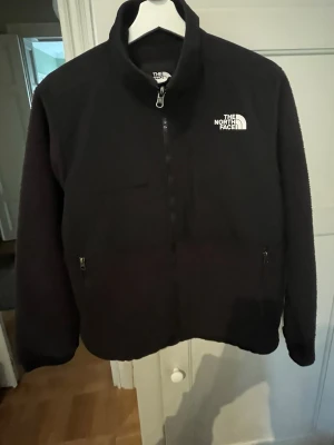 Svart fleecejacka från The North Face - Säljer en svart fleecejacka från The North Face som är unisex. Storlek M för kvinnor och S för män. Normal pass form Jackan har två sidofickor med dragkedja och två bröstfickor. Materialet är mjuk fleece med förstärkta partier på bröst och axlar. Perfekt för kyliga dagar. Pris kan diskuteras vid en snabb affär!