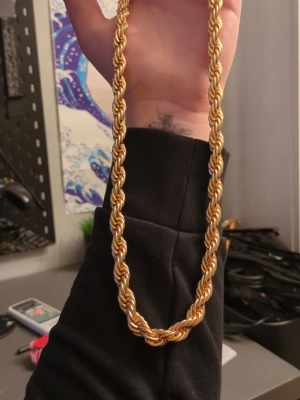 Tjockt guldfärgat cordell halsband 8MM - Säljer ett chunky halsband i guldfärgad metall med repkedje-design. Halsbandet har en vriden, flätad look som ger en riktigt fet vibe och stängs med en enkel ringlås. Perfekt för dig som vill sticka ut och addera lite bling till din outfit.