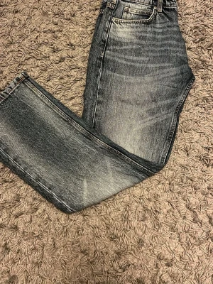Jeans - Säljer ett par snygga blåa jeans med tvättad look och raka ben. Jeansen har klassisk femficksmodell och normal midja. Materialet är denim i bomull och färgen har snygga slitningar för en trendig vintagekänsla.