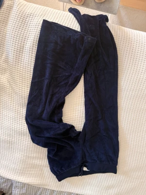 Mörkblå mjukisbyxor från Gina Tricot - Mörkblå mjukisbyxor från Gina Tricot i mjukt och skönt material. Byxorna har resår i midjan och vid bensluten för en avslappnad passform. Perfekta för chill dagar hemma eller när du vill vara bekväm.