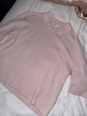 Ljusrosa stickad tröja  - Mysig ljusrosa stickad tröja från Gina Tricot med rund halsringning och breda ribbade muddar vid ärmslut och nederkant. Tröjan har en avslappnad passform och är perfekt för lager på lager. Materialet känns mjukt och skönt mot huden.