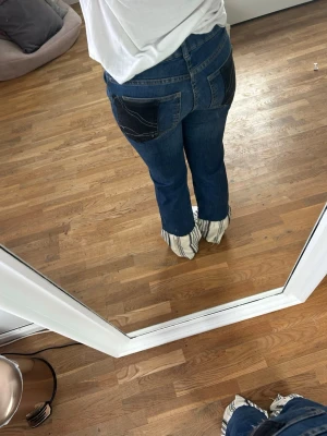 Mörkblå bootcut jeans med fickdetalj - Säljer ett par mörkblå bootcut jeans. Jag har sytt om dom till lite mer bootcut passform nedtill, med ett randigt tyg. Jag har även sytt om fickorna till en cool design. Jeansen har ett väldigt stretchigt denimtyg vilket ger en snygg och bekväm passform. (W är S, innebenslängd 80cm) 