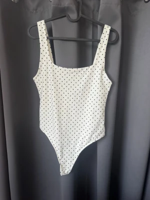Vit prickig body från Zara - Snygg vit prickig body som är helt oanvänd och köpt för en månad sedan. Den är lite djupare i ryggen och är i väldigt skönt material. Den är storlek L men passar dig som har S/M! 