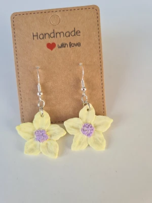 Handgjorda gula blomörhängen - Supersöta handgjorda örhängen i form av ljusgula blommor med lila mitt. Örhängena har silverpläterade krokar och är gjorda för hand av mig i polymerlera  