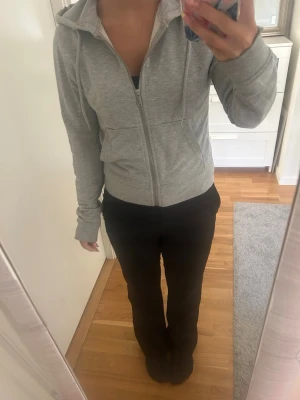 Ljusgrå zip hoodie med huva - Säljer en ljusgrå hoodie med dragkedja och huva. Tröjan har långa ärmar, fickor framtill och justerbara snören i huvan. Perfekt för en avslappnad och enkel stil. Materialet känns mjukt och bekvämt, passar till det mesta i garderoben.
