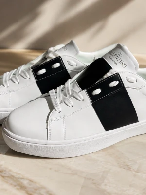 Vita sneakers från Valentino Garavani - Snygga vita sneakers från Valentino Garavani med en bred svart detalj över sidan och vita skosnören. Skorna har en klassisk låg profil och är tillverkade i slätt läder. Perfekta för dig som vill ha en clean och stilren look.