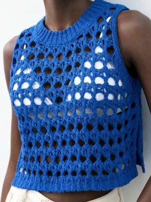 Blå stickad virkad väst - Snygg blå stickad väst med grovt virkat mönster och ribbad halsringning. Ärmlös och croppad modell som ger en trendig look. Perfekt att styla över ett linne eller t-shirt. Materialet ser ut att vara mjukt garn.