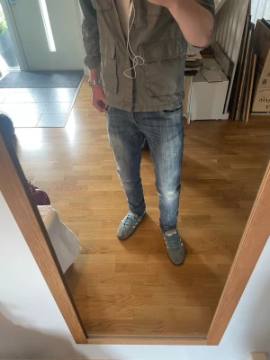 Blå slitna slim fit jeans - Säljer ett par blå slim fit jeans med slitningar och tvättade detaljer. Jeansen har klassisk femficksmodell och normal midja. Perfekta för en avslappnad och trendig look. Materialet är denim i bomull. L34 men sitter mer som L32