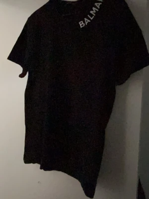 Svart B tröja - Snygg svart Balmain Paris T-shirt som är perfekt för sena somrar.