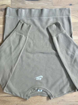 Beige sweatshirt från Nike storlek 156-166cm - Snygg beige sweatshirt från Nike med diskret logga framtill. Tröjan har rund halsringning, långa ärmar och breda muddar vid ärmslut och nederkant. Tillverkad i mjukt bomullsmaterial för en avslappnad och clean look. 155-166cm