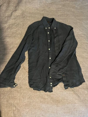 Mörkblå linneskjorta från Morris - Snygg mörkblå skjorta från Morris i 100% linne. Klassisk modell med långa ärmar, vita knappar och krage. Perfekt för dig som gillar stilrena och bekväma plagg. Passar till många olika outfits och är riktigt skön under varmare dagar.