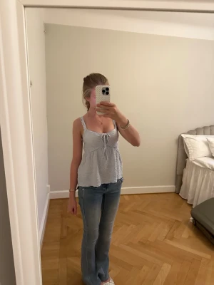 Ljusblå linnetopp med knyt - Söt ljusblå linnetopp med vita prickar och knyt framtill. Toppen har breda axelband och en avslappnad passform som ger en luftig känsla. Perfekt till jeans eller kjol för en fräsch sommarlook.