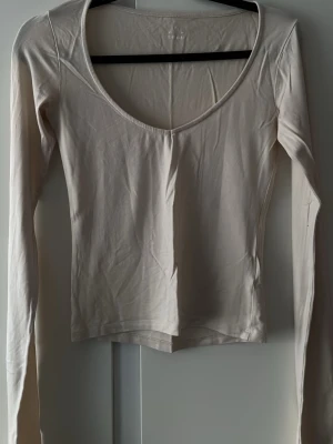 ADSGN topp - Säljer en beige långärmad topp från A-DSGN med djup v-ringning. Knappt använd, mycket gott skick! Köpt för 499kr. 