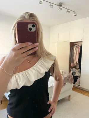 Svart offshoulder topp med volang💓 - Säljer en svart offshoulder topp med bred vit volang. Toppen är ärmlös och har en croppad passform som ger en trendig look💓 inga defekter, storlek L men passar även mig som brukar ha S/M💓