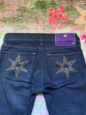 Victoria Beckham Lågmidjade bootcut jeans - Snygga mörkblå lågmidjade bootcut jeans från Victoria Beckham😍De har dekorativa stjärnor i diamanter på bakfickorna och gulddetaljer! Jeansen har klassisk femficksdesign och utsvängda ben🤍 Perfekta för dig som vill sticka ut med coola detaljer och unik look! Passar så bra till alla plagg, vardagligt och finare events🩷Materialet är mjukt och skönt, inte hårt! Storlek liten XS/stor XXS. Mått cm: midja 35, gren 18, innerben 83💋Använda några gånger men utan defekter! Såå unika och Y2k/2000s vibe❤️