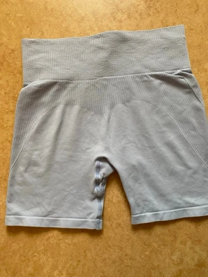 Ljusblå träningsshorts  - Säljer ett par ljusblå träningsshorts från lager 157, lappen i shortsen håller på att lossna men påverkar inte utseende eller användning. Säljer eftersom dem inte kommer till användning 