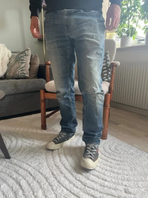 Levi’s 511 Slim Distressed Jeans W31 L32 Ripped Knee - snygg naturlig distressed-look. Riven detalj vid ena knät ger ett äkta, välanvänt uttryck – perfekt för den som vill ha den populära “ripped”-stilen utan att behöva klippa upp ett par själv.  Skick: bra skick, med avsiktligt/naturligt slitage och rivet knä (se bild) Material: denim (bomullsmix) Midja: W31 Innerbenslängd: L32 Modell: 175 cm / 65 kg — bär vanligtvis W30/32, sitter true to size på bild