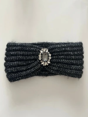 Svart stickat hårband med strass - Väldigt fint hårband med smycke i mitten.  Bredd: ca 20 cm Längd: ca 8 cm