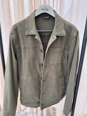 Olivgrön overshirt från Lindbergh - Snygg olivgrön overshirt från Lindbergh i klassisk modell. Jackan har raka linjer, krage och diskreta sömmar. Perfekt för dig som vill ha en stilren och enkel look med en touch av streetwear. En overshirt som är lite distressed. Säljer den för att den inte passar mig, använd två eller tre gånger, så i princip nyskick. Jag är 190 cm lång och den är lite liten för mig, lite för kort i längden. 