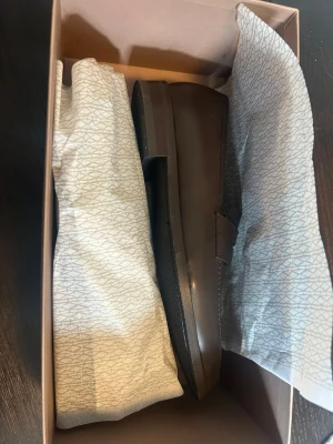 Bruna loafers från Myrqvist - Säljer ett par stilrena bruna loafers från Myrqvist. Skorna är i slätt läder och har klassisk form med låg klack. Perfekta för dig som gillar tidlös och clean stil. Levereras i originalkartong. Storlek 8 vilket motsvarar 42