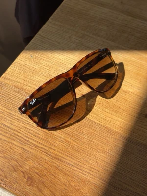 Bruna solglasögon Ray-Ban Boyfriend - Snygga solglasögon från Ray-Ban i klassisk pilotmodell med turtlebrunt mönster på bågarna. Glasen är tonade i brunt och bågarna är tillverkade i plast. Perfekta för dig som vill ha en tidlös och trendig look.k