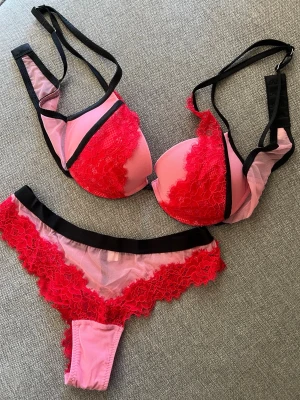 Intimissimi rosa och rött spetsunderklädesset - Säljer ett snyggt underklädesset med bh och trosa i rosa mesh och röd spets. Setet har svarta detaljer och tunna axelband. Bh:n är vadderad och trosan har en låg midja. Perfekt för dig som vill ha något färgglatt och trendigt. Intimissimi