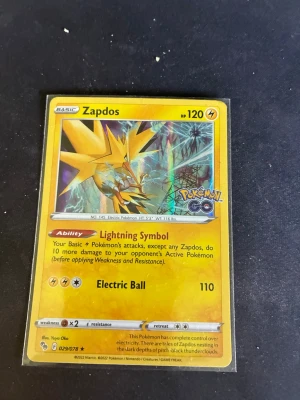 Pokémonkort Zapdos Pokémon GO - Säljer ett Pokémonkort med Zapdos från Pokémon GO-serien. Kortet har gul ram, holografisk effekt och visar Zapdos med 120 HP och attacken Electric Ball. Perfekt för samlare eller Pokémonfans som vill utöka sin kortsamling.