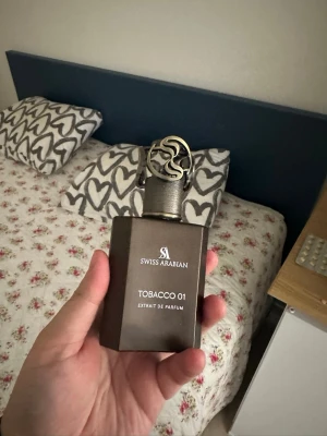 Swiss Arabian Tobacco 01 Extrait de Parfum 50 ml - Tobacco 01 från Swiss Arabian är en Orientalisk kryddig doft för kvinnor och män. Detta är en ny doft. Tobacco 01 lanserades 2024. Parfymören bakom denna doft är Angéline Leporini. Toppnoterna är Plommon, Äpple, Lakrits, Spiskummin och Rosa peppar; hjärtnoterna är Labdanum, Bärnsten, Patchouli och Ylang Ylang; basnoterna är Tobak, Honung, Vanilj, Sandelträ, Musk och Kashmirträ.  OBS! Saknar Original Förpackning och inte intresserad av byte