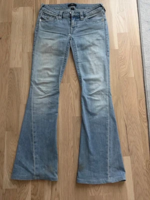 True religion Jeans  - Säljer dessa True religion Joey Low Rise Flare Jeansenw. Innerbens längden är 115cm då byxorna är uppsydda. Dom små fläckarna längs ner tvättas bort innan jag skickar byxorna. Jeansen är i storlek 25 som motsvarar storlek Xs. Pris går att diskutera.