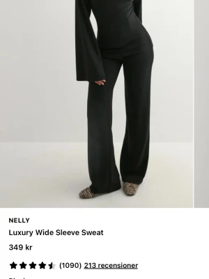 Svart topp med vida ärmar från Nelly - Stilren svart topp från Nelly med långa, vida ärmar och figurnära passform. Toppen har en enkel, elegant design utan mönster och är tillverkad i ett mjukt material som känns bekvämt mot huden. Perfekt för dig som gillar minimalistisk stil.