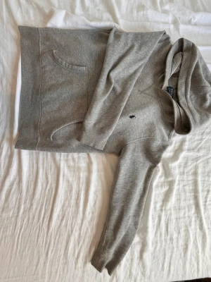 Grå hoodie med ficka framtill - Säljer en stilren grå hoodie med huva och magficka. Perfekt för chill dagar eller när du vill ha en enkel och snygg look. Pris går att diskutera 