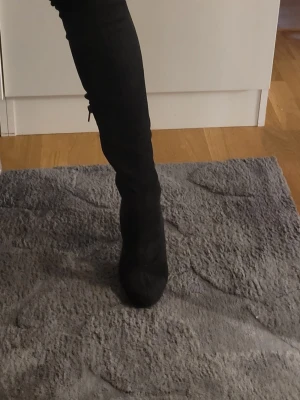 Stl 36/37 Svarta overknee stövlar med smal klack - Säljer ett par svarta overknee stövlar med hög klack och rundad tå. Stövlarna är i ett stretchigt sammets tyg som sitter tight längs benet och har en elegant siluett. Perfekta för dig som vill ha en trendig och snygg look till hösten eller vintern. Använda någon gång, storlek 37 men passar mig som har 36 och smalare fot