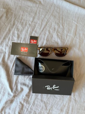 Bruna Ray-Ban solglasögon Wayfarer - Snygga Ray-Ban Wayfarer solglasögon i brunmelerad plast med klassisk form. Kommer med originalfodral, putsduk och box. Perfekta för soliga dagar och ger en cool retrovibe till din stil.