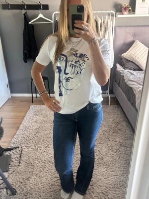Mörkblå bootcut jeans med vita sömmar - Säljer ett par mörkblå bootcut jeans med vita kontrastsömmar och klassisk femficksdesign. Jeansen har låg midja och är snygg i passformen. Bakfickorna har dekorativa sömmar som ger extra stil.