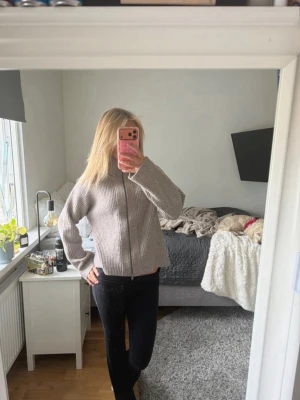 Beige stickad tröja med dragkedja - Säljer en beige stickad tröja från 157 med dragkedja framtill. Tröjan har en rak passform, hög krage och ribbstickad struktur. Perfekt för lager på lager och enkel att matcha med olika outfits.