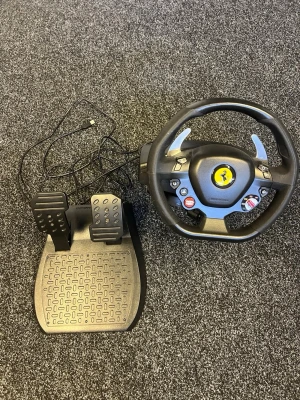 Ratt och pedaler för racing-spel - Säljer en svart racingratt med pedaler, inspirerad av Ferrari-design. Ratten har flera knappar, växlingspaddlar i metall och en tydlig Ferrari-logga i mitten. Perfekt för dig som vill ta din racingupplevelse till nästa nivå på konsol eller PC. Ratten går att användas på ps4-ps5 och pc 