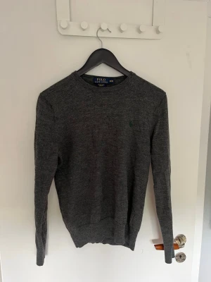 Polo Ralph Lauren stickad tröja - Säljer en stilren grå tröja från Polo Ralph Lauren. Tröjan är långärmad och har en   broderad logga på bröstet. Perfekt för en klassisk och avslappnad look. Storlek M men känns som S