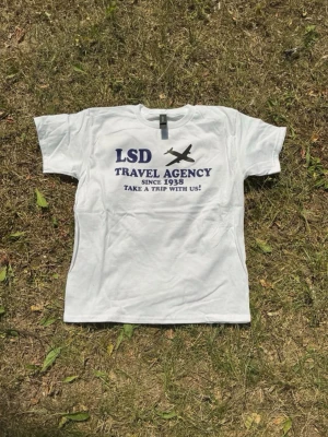 T-shirt LSD Travel Agency - Längd: 64cm Armhåla till armhåla: 48cm Barnstorlek L, passar S/M Hör av er vid frågor!