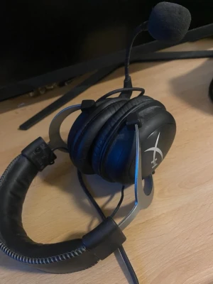 HyperX Cloud II gaming headset - Säljer ett HyperX Cloud II over-ear headset i svart med löstagbar mikrofon. Sköna öronkuddar i konstläder och robust metallbåge. Perfekt för gaming med tydligt ljud och bekväm passform. Kabelanslutning och klassisk HyperX-logga på kåporna.