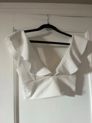 Söt vit topp - Söt vit men ganska kort topp från NLY ONE. Den har fina volanger och är perfekt som sommarens fest topp!