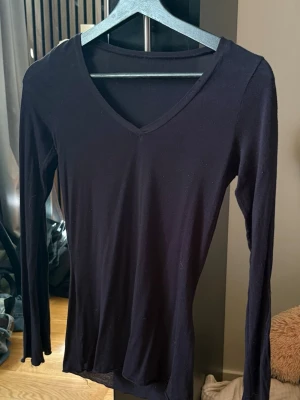 Intimissimi långärmad v-ringad tshirt / topp - En enkel och stilren svart långärmad topp med v-ringning. Tillverkad i mjukt material som sitter skönt mot kroppen. Perfekt att matcha med jeans eller kjol för en clean look.