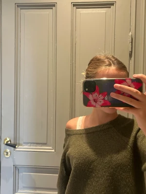 Olivgrön stickad tröja med rund hals - Mysig olivgrön stickad tröja med rund halsringning och avslappnad passform. Tröjan har kortare ärmar och kan bäras off-shoulder för en trendig look. Perfekt att styla med jeans eller kjol för en chill vibe.