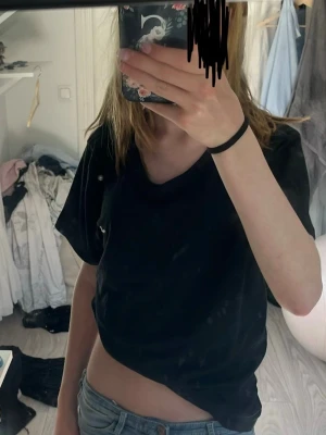 Svart t-shirt med v-ringning - En svart t-shirt med v-ringning och korta ärmar. T-shirten har en avslappnad passform och är tillverkad i mjukt bomullsmaterial. Perfekt för en enkel och stilren look.