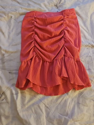 Rosa volangkjol från Gina Tricot - Supersnygg rosa kjol från Gina Tricot med volangkant och rynkade detaljer framtill. Kjolen har en kortare passform och är tillverkad i ett lätt, strukturerat tyg som ger en cool look. Perfekt för dig som vill sticka ut lite extra!